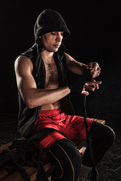 Zbliżenie dłoni z bandażem muskularnego mężczyzny trenującego kickboxing na czarno