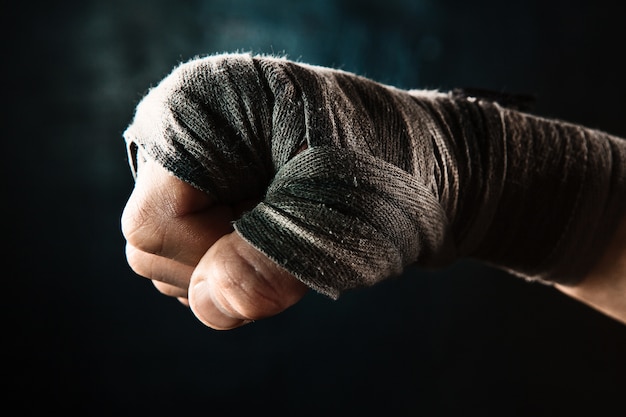 Bezpłatne zdjęcie zbliżenie dłoni z bandażem muskularnego mężczyzny trenującego kickboxing na czarno