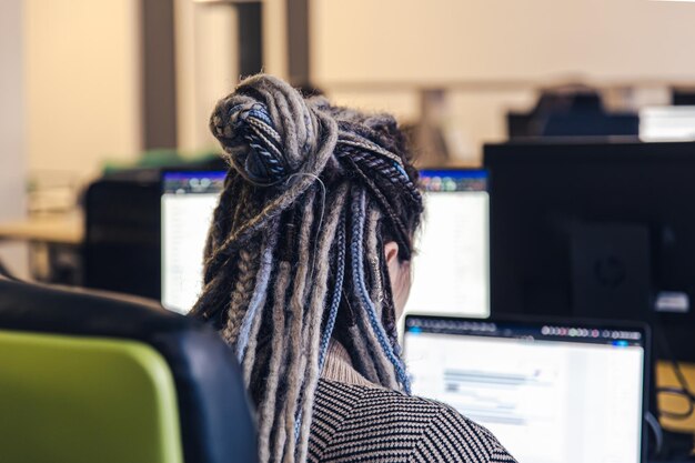 Zbliżenie dredów dziewczyny pracującej przy komputerze, widok z tyłu