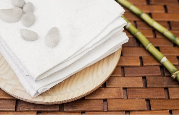 Zbliżenie kamyków; ręcznik i bambus roślina na drewnianym stole