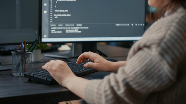 Zbliżenie kaukaski ręce kodera oprogramowania, wpisując na klawiaturze przed ekranami komputera z interfejsem programowania. Programista baz danych siedzący przy biurku pisania algorytmu dla agencji it.