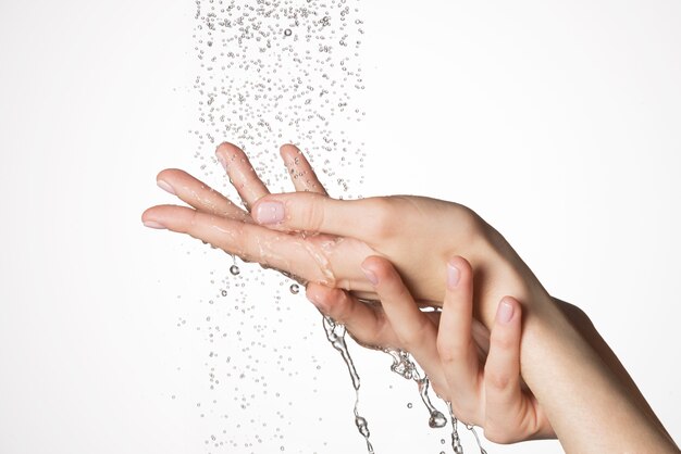Zbliżenie kobiece dłonie pod strumieniem rozpryskiwania wody - koncepcja pielęgnacji skóry
