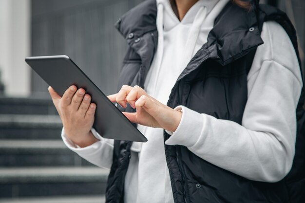 Zbliżenie kobieta używa tabletu na rozmytym tle miasta