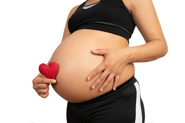 Zbliżenie: kobieta w ciąży, trzymając znak serca na brzuchu