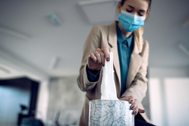 Zbliżenie kobiety przedsiębiorcy biorącej chusteczkę podczas pracy w biurze podczas pandemii koronawirusa
