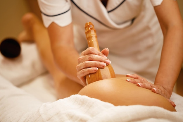 Zbliżenie kobiety wykonującej masaż antycellulitowy podczas zabiegu maderoterapii w spa
