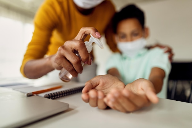 Zbliżenie matki dezynfekującej ręce syna z powodu pandemii wirusa