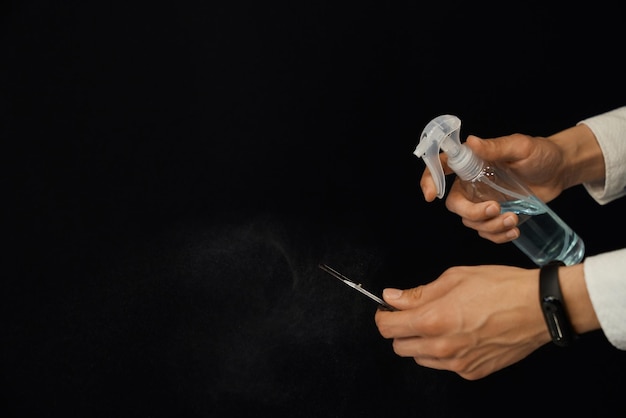 Zbliżenie męskich rąk dezynfekujących nożyczki przed strzyżeniem