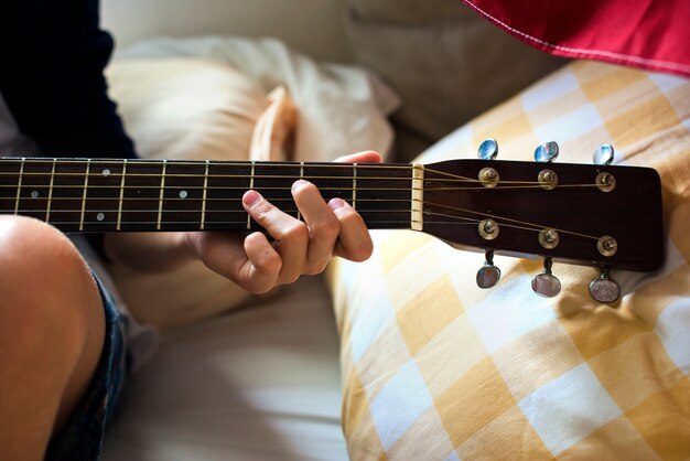 Zbliżenie młoda caucasian chłopiec bawić się gitarę na łóżku
