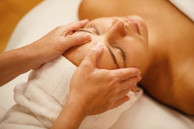 Zbliżenie młodej kobiety korzystających z masażu głowy podczas zabiegów kosmetycznych w spa