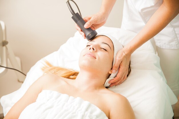 Zbliżenie młodej kobiety w trakcie sesji terapii twarzy w gabinecie kosmetycznym i spa