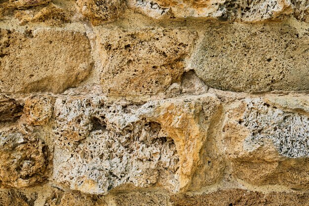 Zbliżenie muru starożytnej ściany z miękkiego piaskowca, która została zniszczona przez czas naturalnego kamienia pomysł na tło lub wnętrze