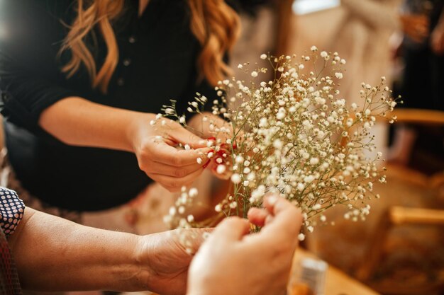 Zbliżenie na dwie nierozpoznawalne kobiety robiące układanie kwiatów przed ceremonią ślubną