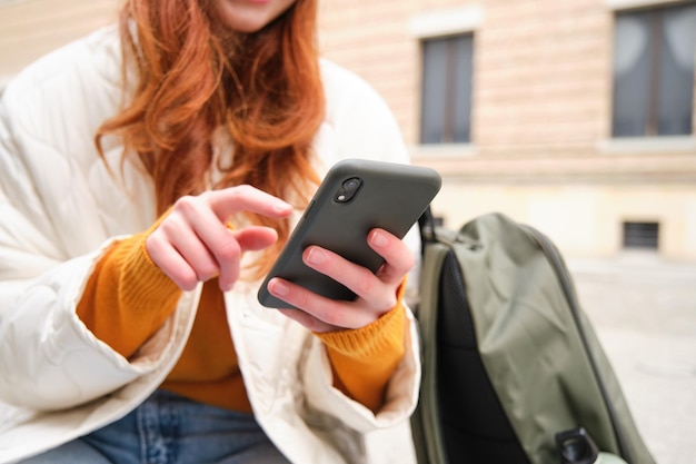 Zbliżenie na kobiece ręce wpisując na telefonie komórkowym za pomocą aplikacji na smartfony dziewczyna z typami telefonów siedzi