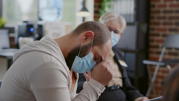 Bezpłatne zdjęcie zbliżenie na mężczyznę płaczącego z powodu problemów ze zdrowiem psychicznym na spotkaniu terapeutycznym. zdesperowany dorosły proszący o pomoc i radę w leczeniu uzależnienia i depresji podczas sesji grupy wsparcia.