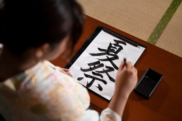 Zbliżenie na nauczyciela wykonującego japońską kaligrafię, zwaną shodo