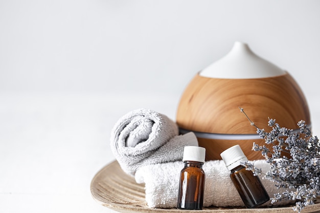 Bezpłatne zdjęcie zbliżenie na nawilżacz powietrza, naturalne olejki aromatyczne, ręczniki i gałązki lawendy. aromaterapia i tło koncepcji opieki zdrowotnej