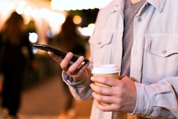 Zbliżenie na ręce trzymające filiżankę i telefon