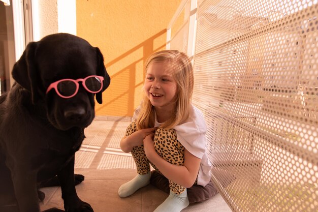 Zbliżenie na słodką młodą dziewczynę bawiącą się ze swoim czarnym psem w domu