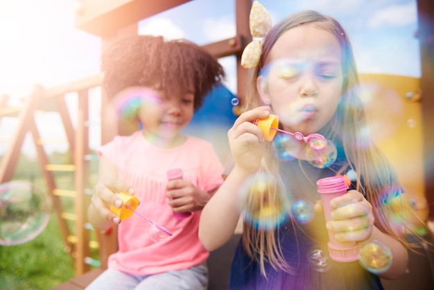 Zbliżenie na szczęśliwe dzieci bawiące się bańkami mydlanymi
