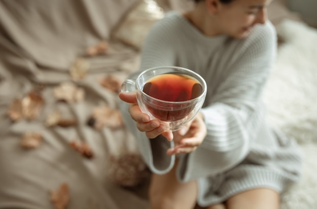 Zbliżenie na szklaną filiżankę herbaty na niewyraźne tło w rękach kobiet.
