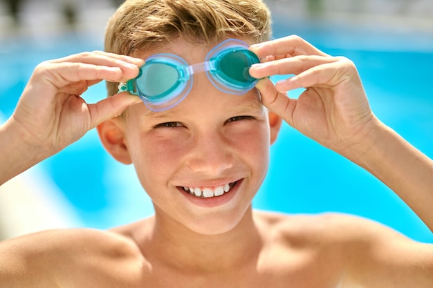 Zbliżenie na twarz chłopca dotykającego okularów pływackich