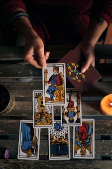 Zbliżenie na wróżkę wyświetlającą karty tarota na drewnianym stole