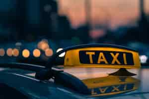 Bezpłatne zdjęcie zbliżenie na znak taksówki w ciepłych kolorach zachodu słońca ze światłami bokeh w tle