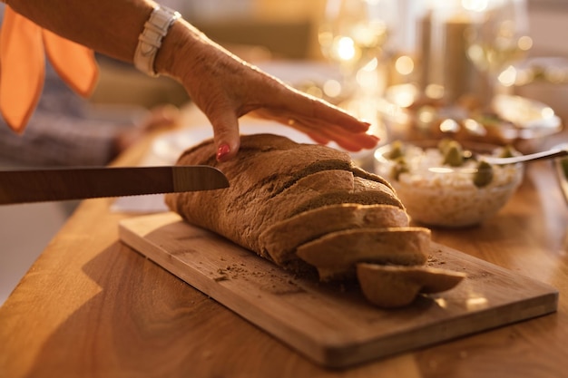 Zbliżenie nierozpoznawalnej kobiety krojącej bochenek chleba