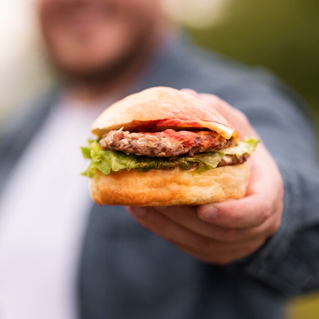 Zbliżenie niewyraźne mężczyzna trzyma burgera