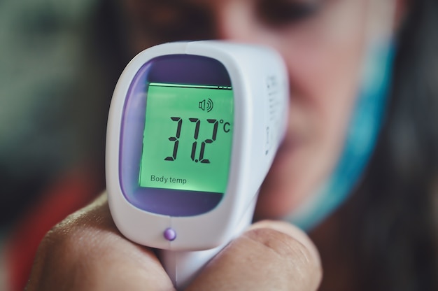 Bezpłatne zdjęcie zbliżenie osoby mierzącej temperaturę termometrem cyfrowym