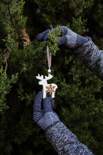 Bezpłatne zdjęcie zbliżenie osoby w rękawiczkach dekorowanie choinki z ornamentem