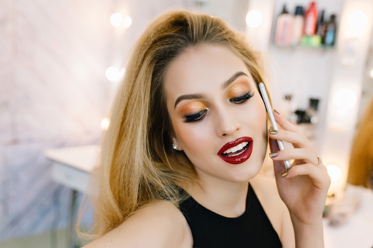 Bezpłatny plik Zdjęcie zbliżenie portret modny model z stylowy makijaż, mówiąc na telefon w salonie fryzjerskim