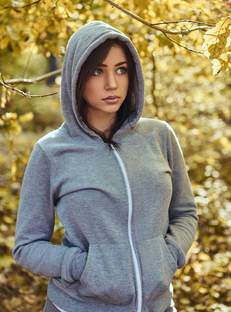 Zbliżenie portret uroczej dziewczyny w szarej bluzie z kapturem w jesiennym parku