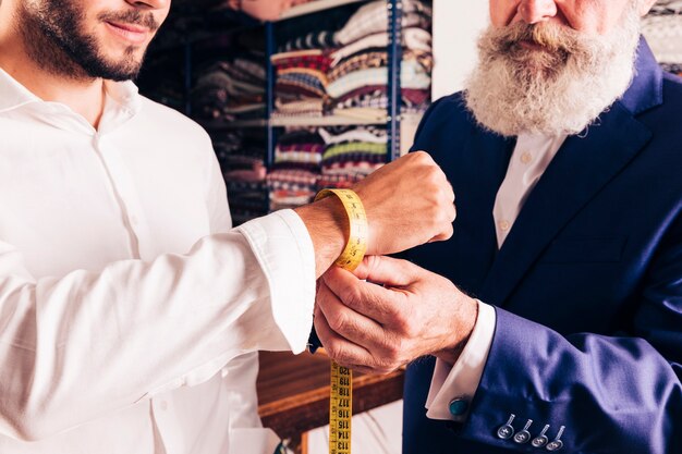 Zbliżenie projektanta mody, który mierzy nadgarstek swojego klienta