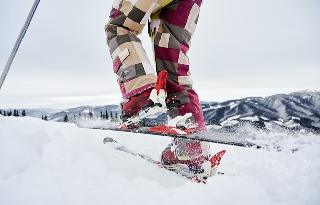 Zbliżenie przycięte zdjęcie nóg narciarza i nart robiących krok do przodu