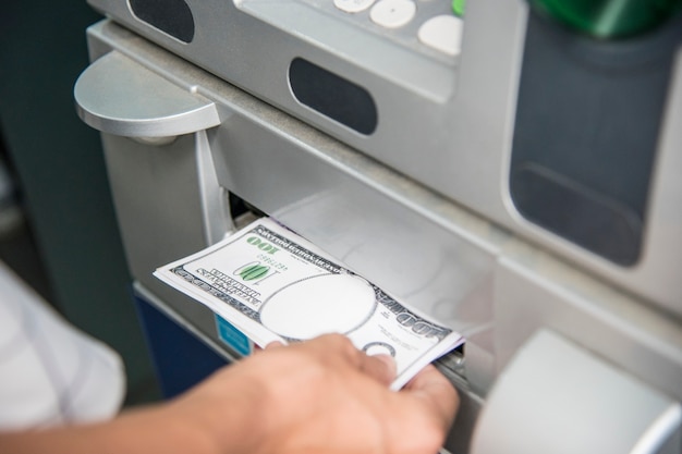 Zbliżenie ręka dostaje pieniądze od ATM