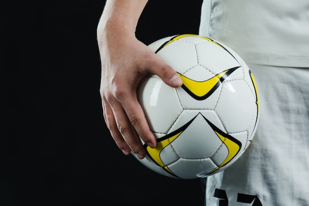 Zbliżenie ręki trzymającej piłkę nożną