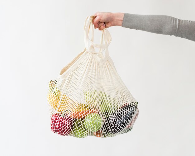 Zbliżenie ręki trzymającej torbę wielokrotnego użytku z warzywami i owocami