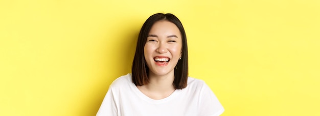 Bezpłatne zdjęcie zbliżenie szczęśliwej młodej kobiety, która dobrze się bawi, uśmiechając się i śmiejąc beztrosko stojąc w białej koszulce