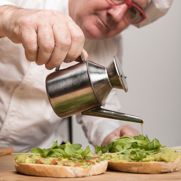 Zbliżenie szef kuchni, dodając olej do guacamole