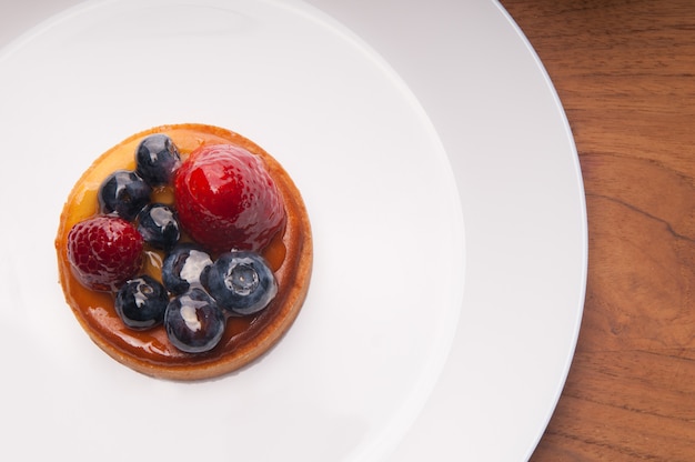 Zbliżenie wyśmienicie mini tarta z jagodami na bielu talerzu