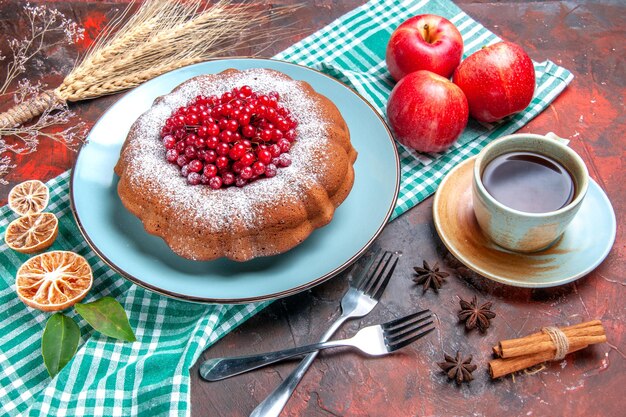 Zbliżenie z boku ciasto filiżanka herbaty widelce ciasto trzy jabłka na obrusie pszenne kłosy