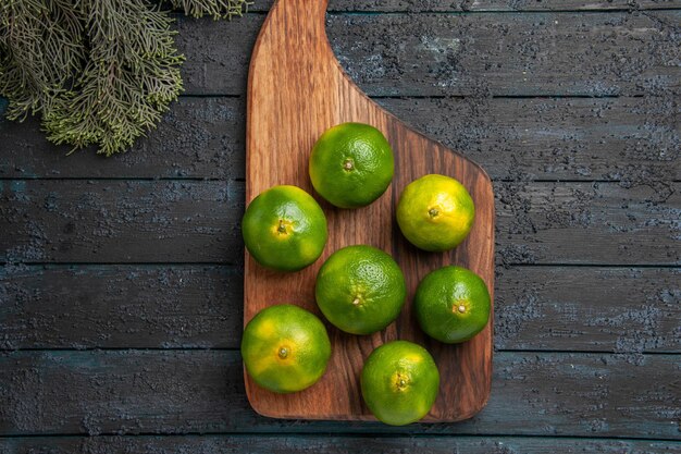 Bezpłatne zdjęcie zbliżenie z góry limonki i gałęzie limonki na desce kuchennej obok gałęzi drzew