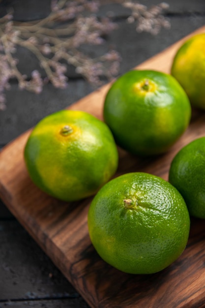 Zbliżenie z góry limonki na stole limonki na desce na desce do krojenia obok gałęzi drzew