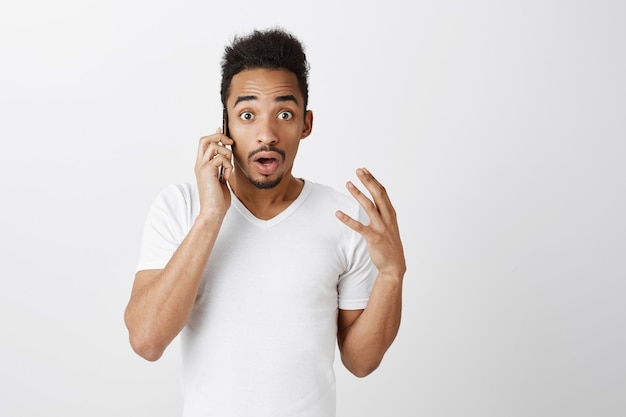Zbliżenie zaskoczony facet Afroamerykanin rozmawia przez telefon i wygląda na zdumionego