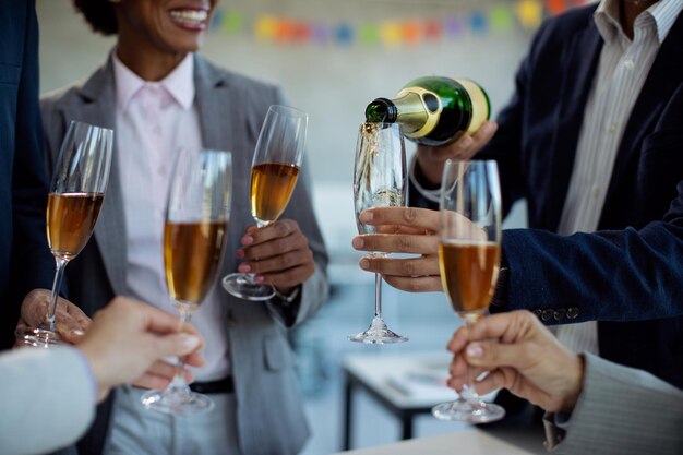 Zbliżenie zespołu biznesowego pijącego szampana na imprezie biurowej