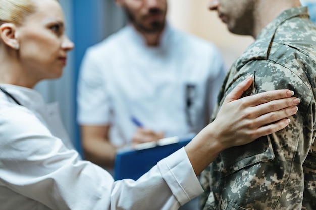 Zbliżenie żołnierza pocieszanego przez pracowników służby zdrowia w klinice