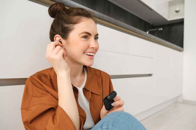 Bezpłatne zdjęcie zbliżony portret atrakcyjnej uśmiechniętej kobiety zakłada bezprzewodowe słuchawki, aby słuchać muzyki