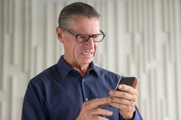 Zdegustowany Starszy człowiek patrząc na ekran Smartphone